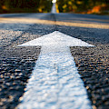 © studioworkstock | freepik.com | Nahaufnahme eines weißen Pfeils auf einer Asphaltstraße mit Sonnenlicht...