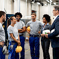 © Drazen Zigic | freepik.com | Junge glückliche Arbeiterin und ihre Kollegen kommunizieren mit...
